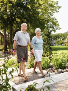 Senior Caucasian couple holding hands and walking outdoors in park.
